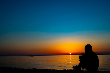 Naklejka na ściany i meble Silhouette of a woman twilight at sunset