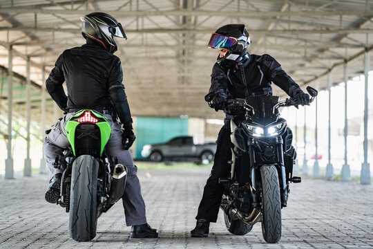 2 man standing and chatting on there motorbikes in an empty warehouse in Bangkok