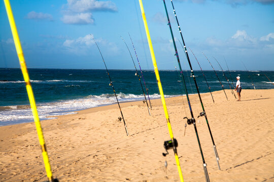 A man tends to his fishing rod on the beach.