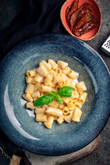 Pasta four penne rigate cheeses on a plate on a dark background. Italian dish 4 cheeses - quattro formaggi, top view