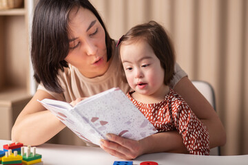 teacher and child girl with down syndrome with a book,education and development of children
