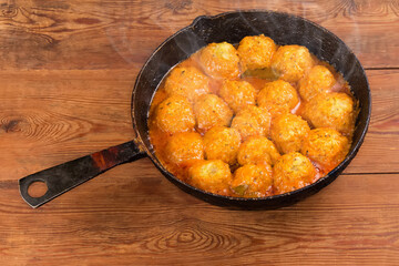 Meatballs with rice in sauce in pan on rustic table