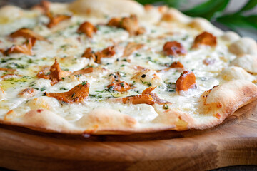 Pizza with chanterelles, cheese and rosemary. Italian pizza with mushrooms and herbs on a wooden board. Close-up, selective focus