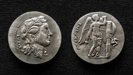 Ancient Greek coin isolated on black background, macro top view of vintage silver money, woman face...