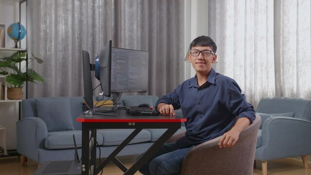 Asian Boy Programmer Smiling To Camera While Creating Software Engineer Developing App, Program, Video Game On Desktop Computer At Home. Terminal With Coding Language 
