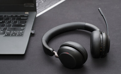 Black wireless headset on office desk near a laptop
