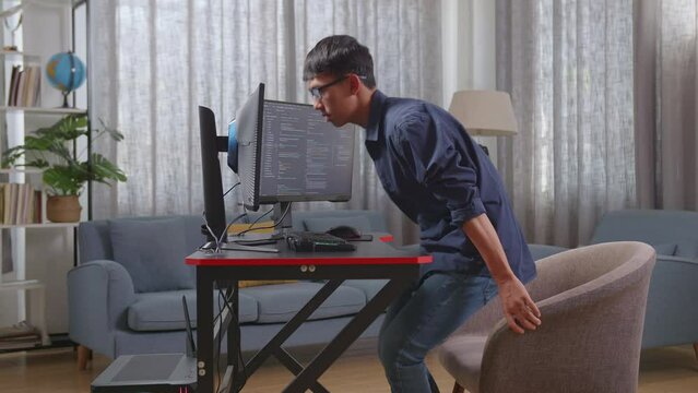 Asian Boy Programmer Walking Into The Working Space Before Sitting To Creating Software Engineer Developing App, Program, Video Game On Desktop Computer At Home
