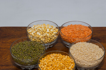 Bowls full of varieties of pulses spread over a wooden table with copy space