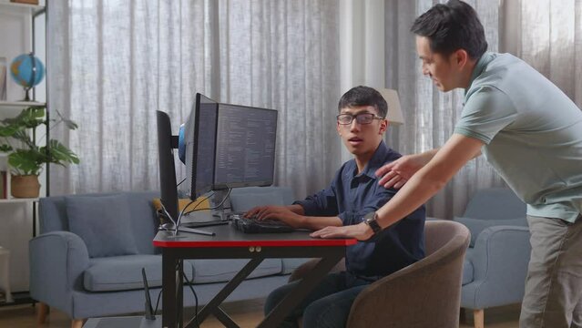Asian Father Teaching His Son Creating Software Engineer Developing App, Program, Video Game On Desktop Computer At Home. Terminal With Coding Language
