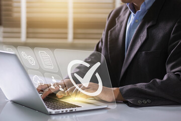 Businessman working on labtop with check mark symbol and standard quality control. The concept of...