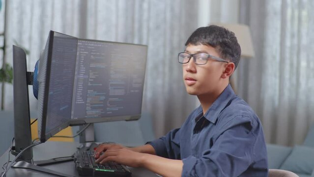 Asian Boy Programmer Smiling To Camera While Creating Software Engineer Developing App, Program, Video Game On Desktop Computer At Home. Terminal With Coding Language 
