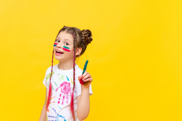 The girl points up. A child stained in paint on a yellow isolated background. Drawing courses for children. Development of children's creativity.