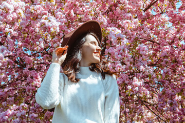 portrait of beautiful caucasian woman with blooming sakura cherry trees