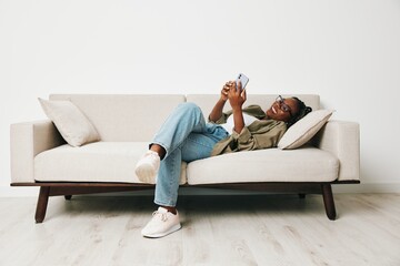 African American woman business freelancer working sitting on the couch at home in the phone,...