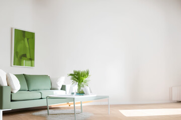 Minimalist living room with white walls and a green sofa.