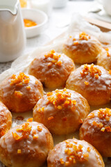 Sweet yeast buns stuffed with rose jam, topped with citrus icing and decorated with candied orange peel, close up view. Traditional yeast pastries