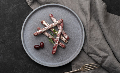 Plate with Spanish sticks of mini fuet on the grey background. flaty lay