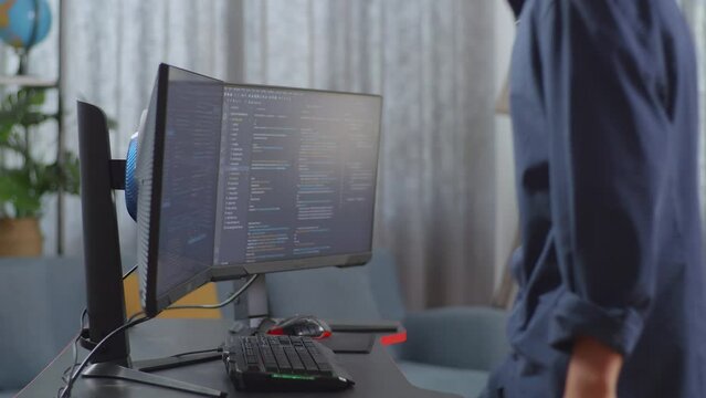 Asian Boy Programmer Walking Into The Working Space Before Sitting To Creating Software Engineer Developing App, Program, Video Game On Desktop Computer At Home
