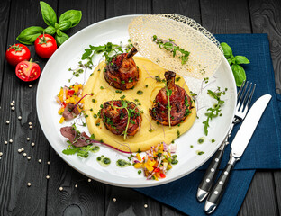 Chicken legs wrapped in bacon with barbecue sauce on mashed potatoes
