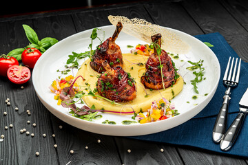 Chicken legs wrapped in bacon with barbecue sauce on mashed potatoes