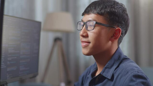 Close Up Of Asian Boy Programmer Creating Innovative Software Engineer Developing App, Program, Video Game On Desktop Computer At Home. Terminal With Coding Language 
