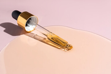 Yellow texture of a drop of whey or olive oil on a pink background. Transparent sample of cosmetic serum. Golden acid cream. Vitamin c. Hyaluronic acid.