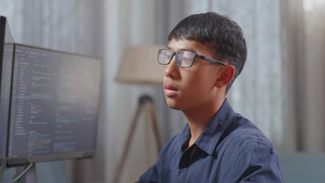 Close Up Of Asian Boy Programmer Yawning While Creating Innovative Software Engineer Developing App, Program, Video Game On Desktop Computer At Home. Terminal With Coding Language 
