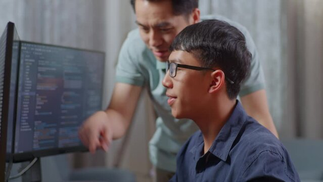 Close Up Of Happy Asian Boy And Male Celebrating Succeed Creating Software Engineer Developing App, Program, Video Game On Desktop Computer At Home. Terminal With Coding Language
