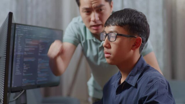 Close Up Of Asian Father Shouting At His Son While Creating Software Engineer Developing App, Program, Video Game On Desktop Computer At Home. Terminal With Coding Language
