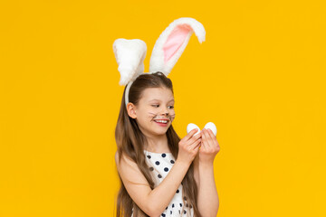 A little beautiful girl is preparing for the Easter holiday and dressed up as an Easter bunny and...