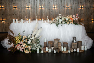 Romantic boho main table. Wedding decor with dried flowers floristry, stumps, and candles, boho style. Pampas grass