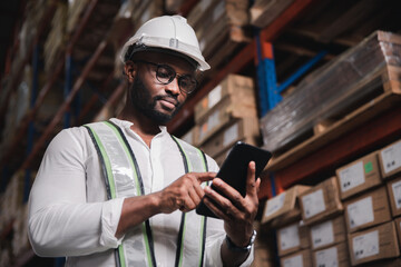 Black male staff using digital tablet working checking stock in logistic warehouse