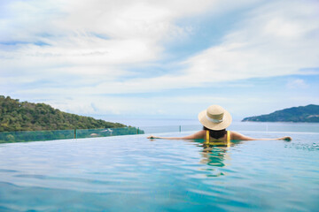 Fototapeta na wymiar Asian travel bikini woman relax in infinity pool resort on phuket beach Thailand