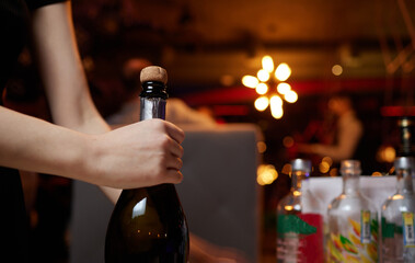 Open the champagne. A woman's hand in the foreground, uncorking a bottle of Prosecco.