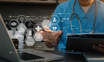 Doctor working with laptop computer and writing on paperwork.