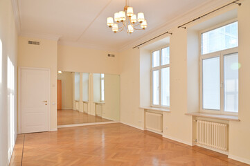 hall in an empty bright apartment with large windows and a shiny floor.