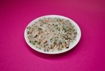 herbal salt on a white plate on a pink background