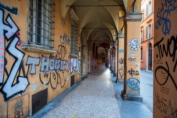 Historic street with yellow walls, columns and graffiti.