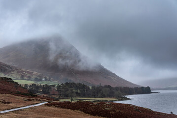 Fototapeta na wymiar Moody dramatic Winter foggy landscape image of Wast Water in English Lake District with thick fog blocking view of mountains in distance