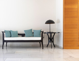 Minimalist interior. Sofa, pillows, lamp, fragment of a wooden cabinet. Lots of space for text on a white wall.