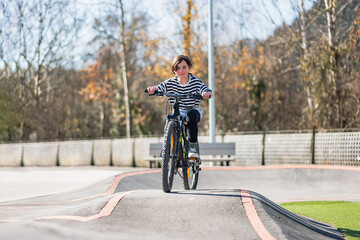 Smiling child riding bike. Learning to ride on run bicycle at skate park.