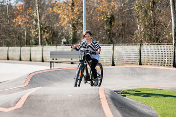 Obraz premium Smiling child riding bike. Learning to ride on run bicycle at skate park.