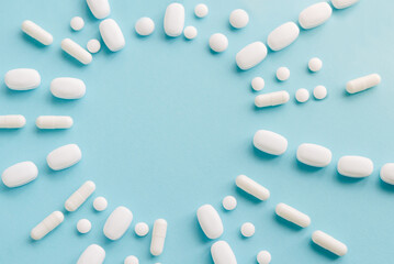Scattered white pills on blue table. Mock up for special offers as advertising, web background or other ideas. Medical, pharmacy and healthcare concept. Copy space. Empty place for text or logo