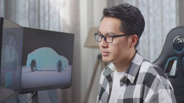 Close Up Of Asian Male Automotive Designer Smiling To Camera While Working On 3D Model Of Ev Car On The Desktop Computers At Home
