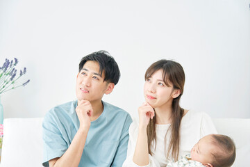 昼寝をする赤ちゃんをを抱っこして考える両親