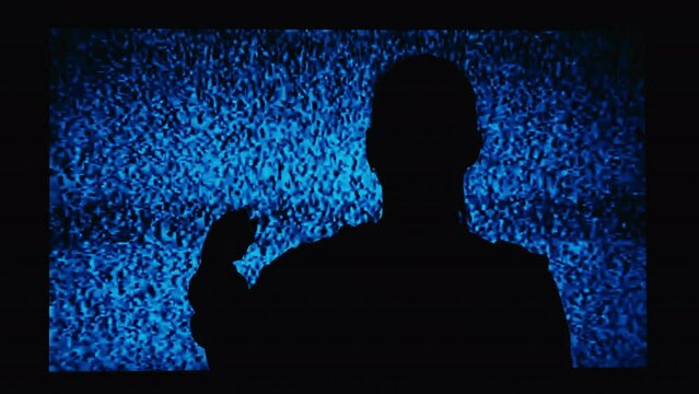 Silhouette of a girl watching TV with noises, shot from the back. Watching TV is a static glitch. Silhouette of a girl watching TV with static noise. Shot behind the shoulders of the model.