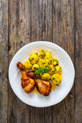 BBQ chicken drumsticks with fried potatoes, lettuce and ketchup on wooden table
