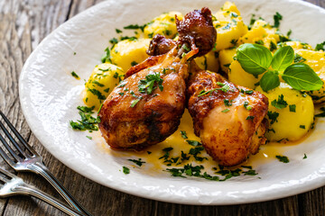 BBQ chicken drumsticks with fried potatoes, lettuce and ketchup on wooden table
