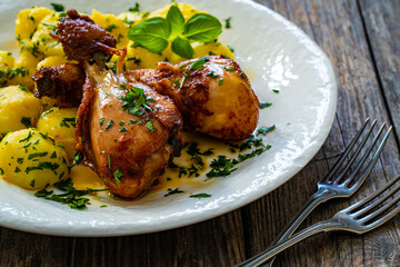 BBQ chicken drumsticks with fried potatoes, lettuce and ketchup on wooden table
