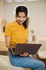 Close up portrait of indian or arabian woman inside home with headset for video call, woman smiling...
